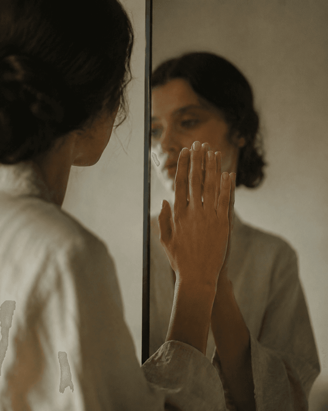A hand touching a mirror, meeting its own reflection.